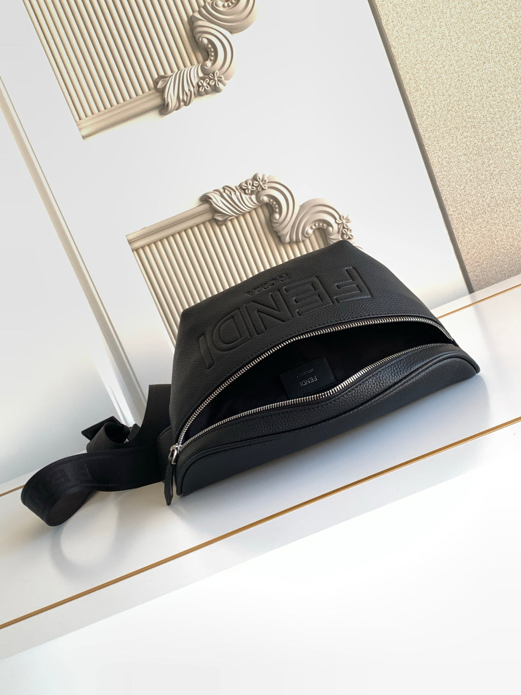 Black Fendi crossbody bag with top zipper and embossed logo on front