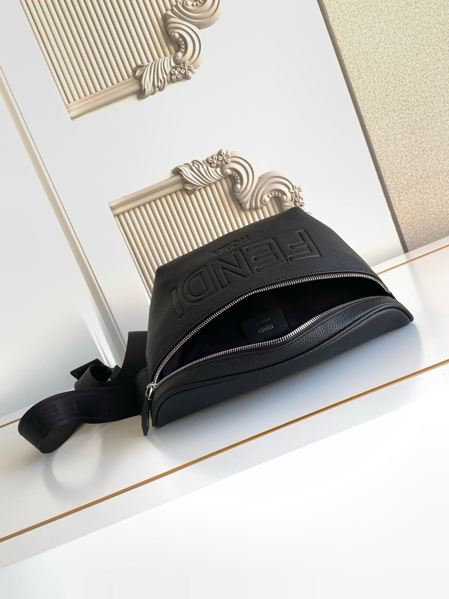 Black Fendi crossbody bag with top zipper and embossed logo on front