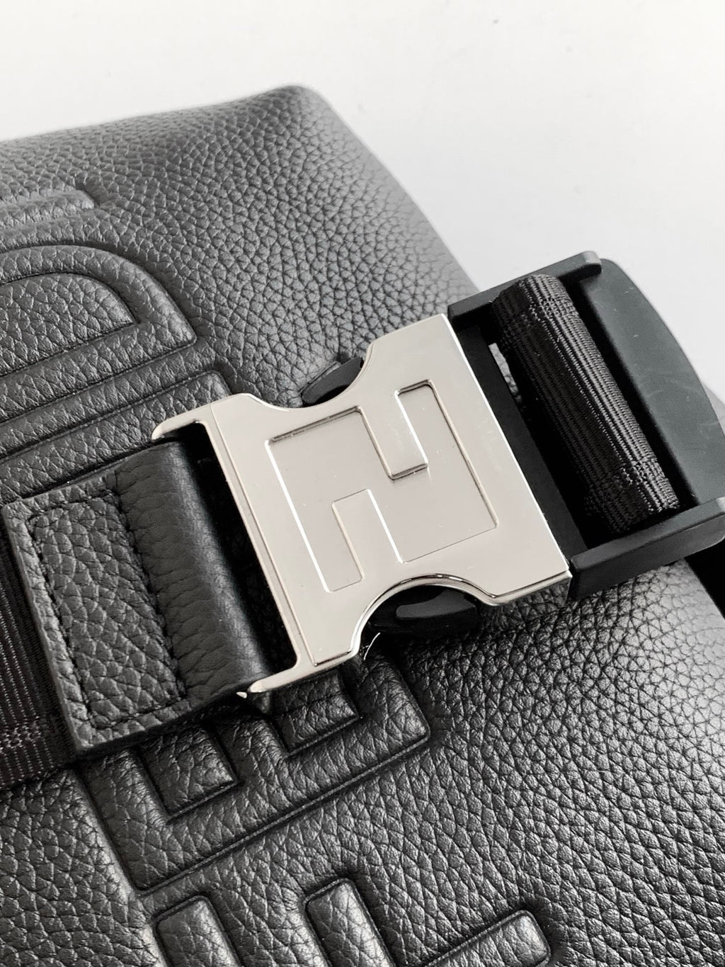Black leather bag detail with silver-tone F buckle and embossed FENDI on surface
