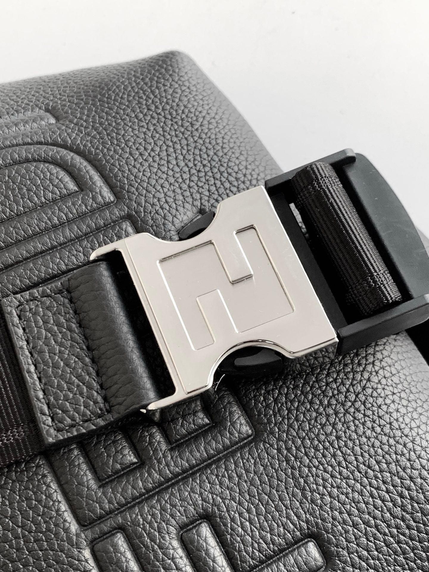 Black leather bag detail with silver-tone F buckle and embossed FENDI on surface