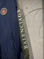 Navy jacket with circular Balenciaga crest patch and diagonal logo tape