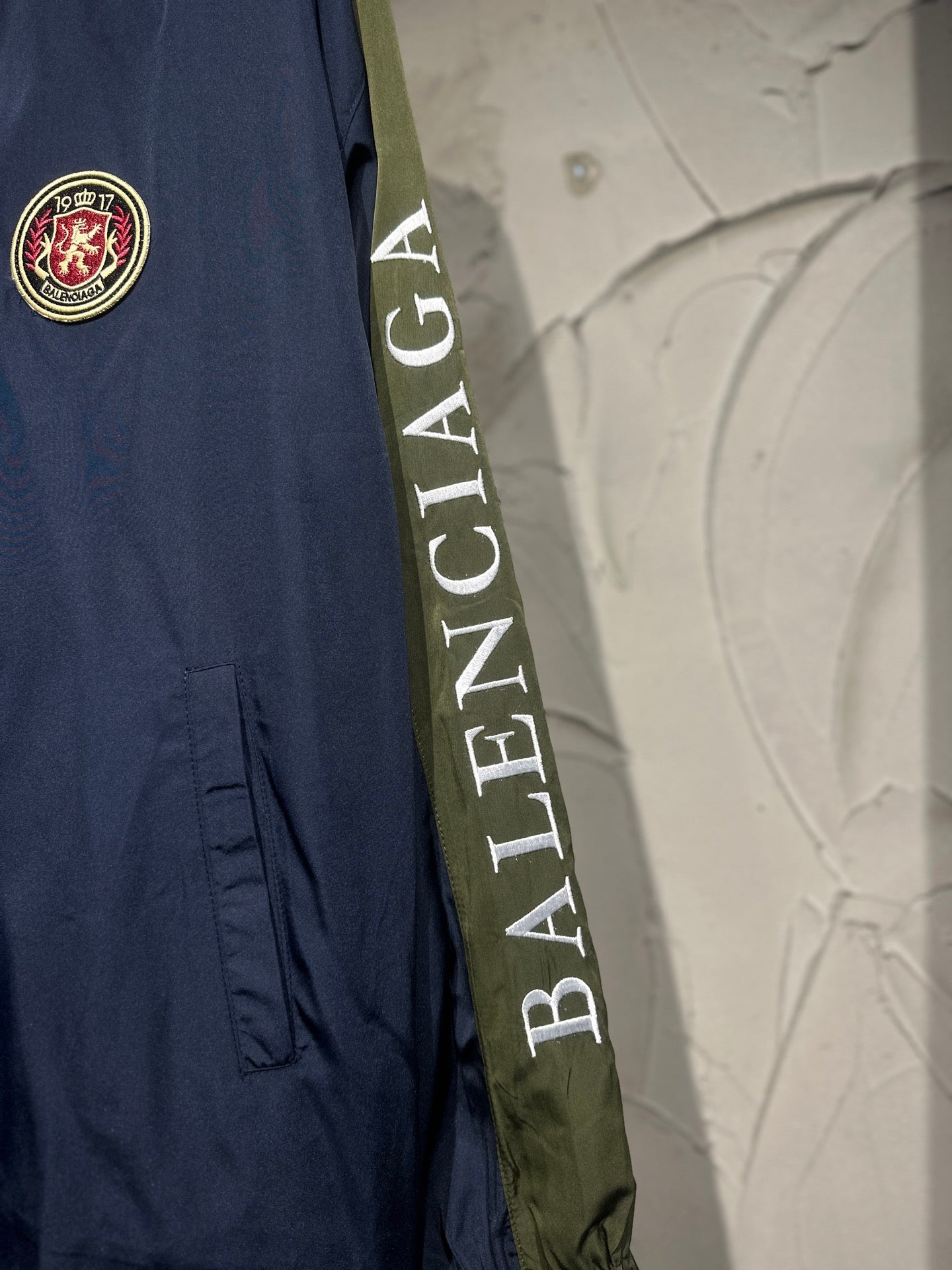 Navy jacket with circular Balenciaga crest patch and diagonal logo tape