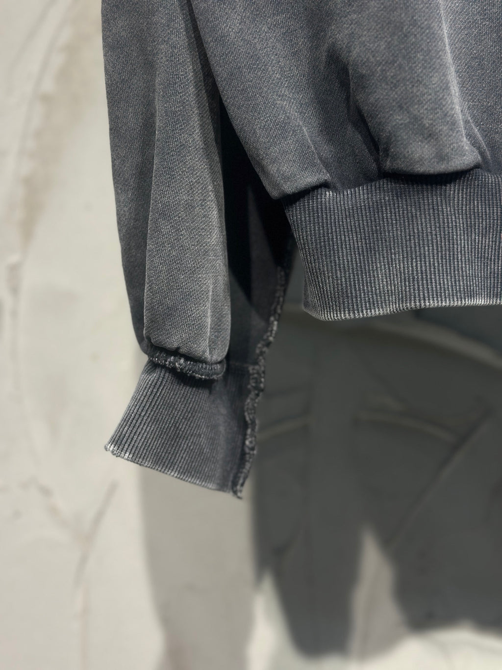 Black hoodie sleeve with ribbed cuff and visible hem stitching at bottom edge