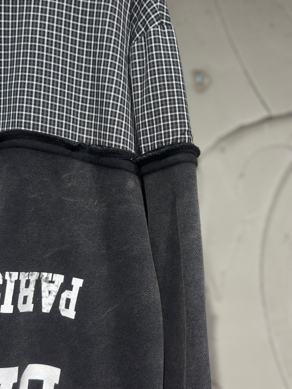 Black hoodie back panel with white graphic partially visible and ribbed hood edge