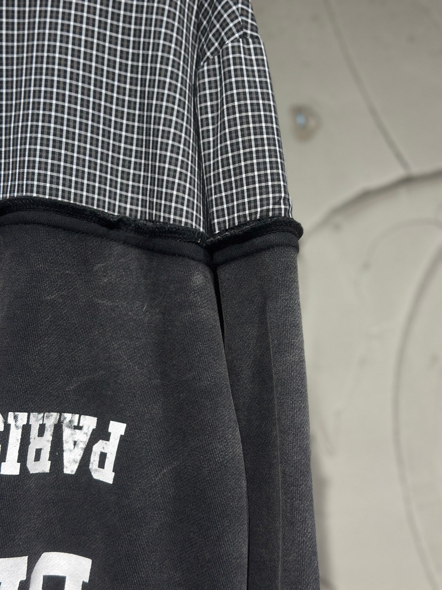 Black hoodie back panel with white graphic partially visible and ribbed hood edge