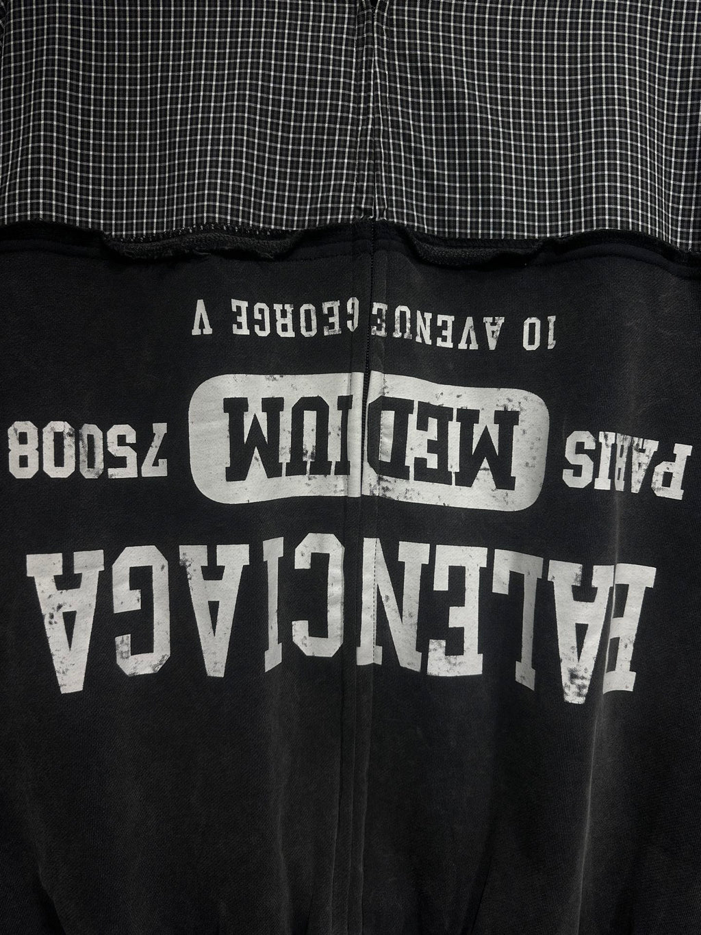 Black hoodie back with large white graphic text and vertical zipper line