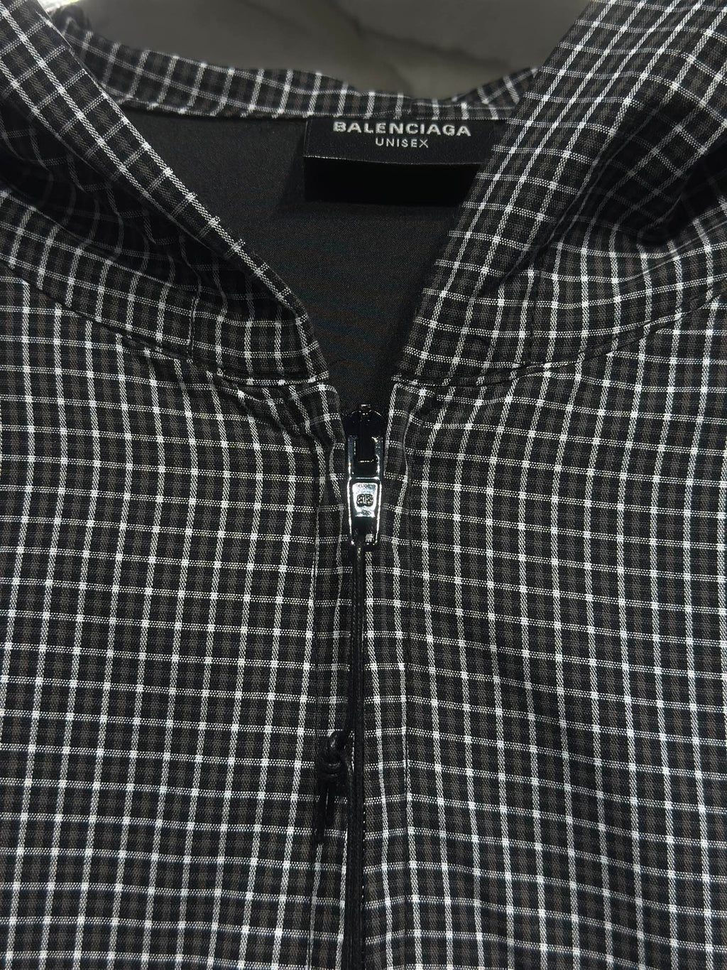 Black and white plaid zip-up hoodie front with centered zipper and chest seam details