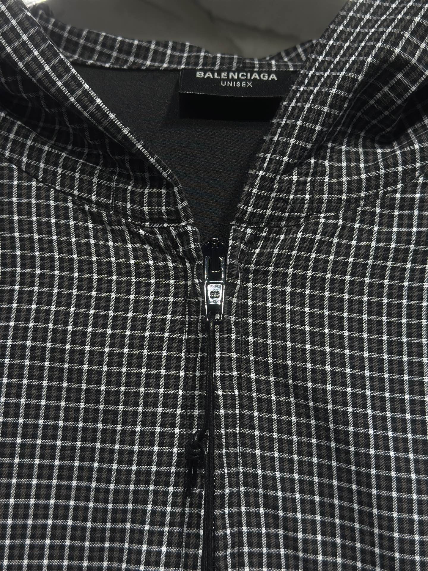 Black and white plaid zip-up hoodie front with centered zipper and chest seam details