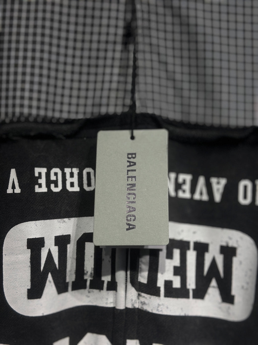 Black hoodie with large white graphic text on chest panel and hanging brand tag