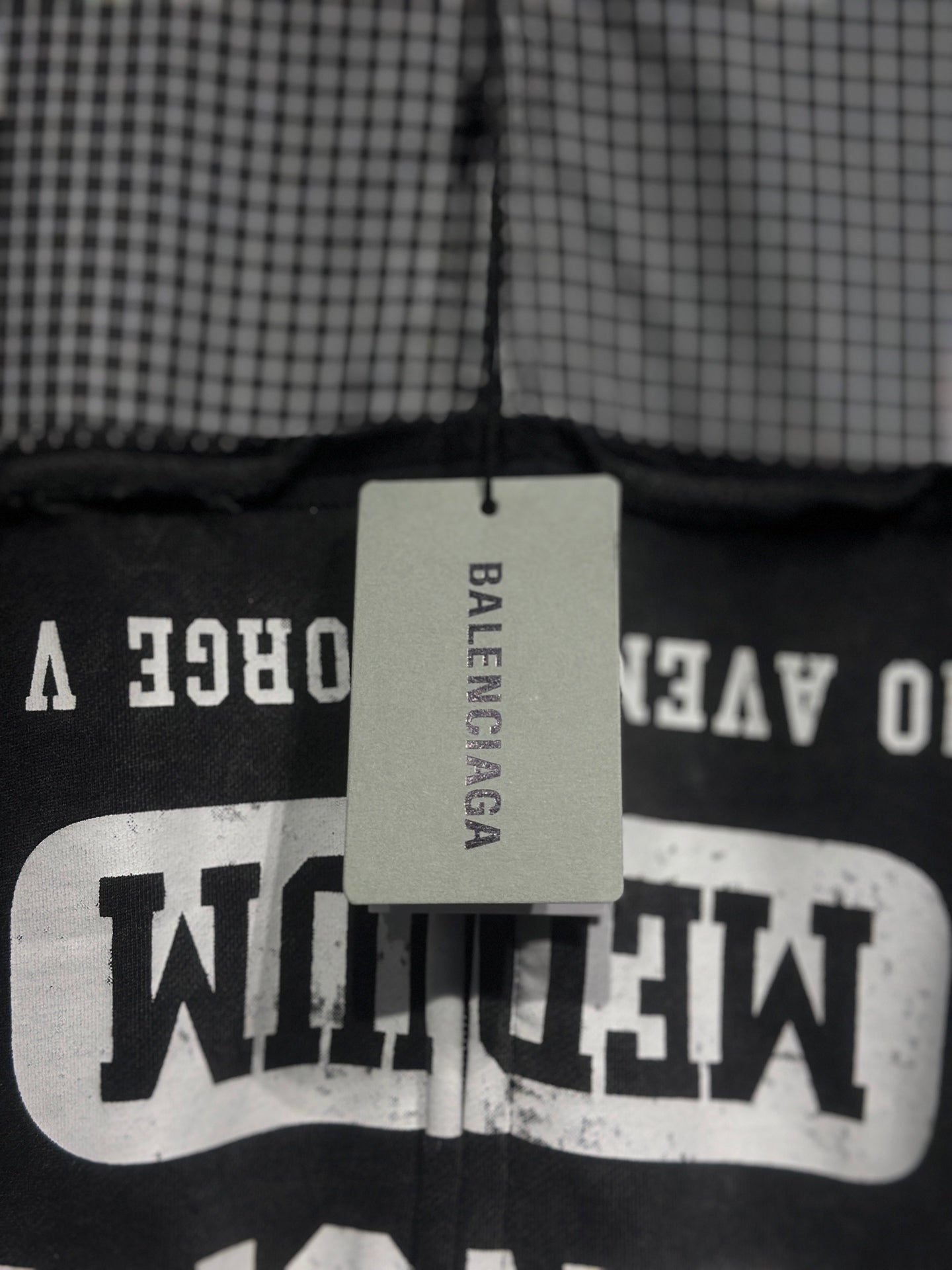 Black hoodie with large white graphic text on chest panel and hanging brand tag