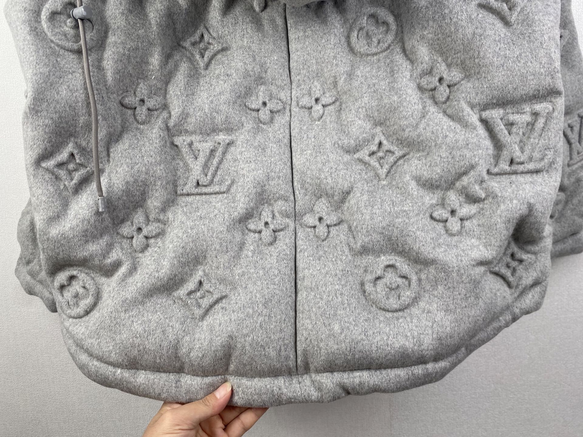 Louis Vuitton hooded puffer jacket lower front close-up, gray monogram center seam