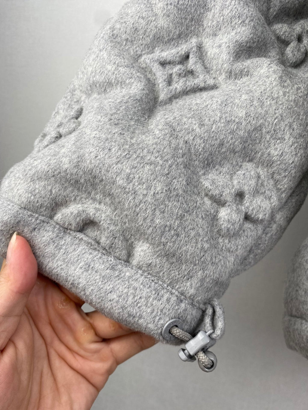 Louis Vuitton hooded jacket sleeve cuff close-up with gray toggles and monogram