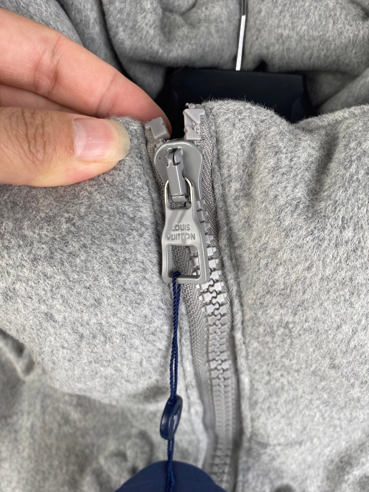Louis Vuitton zipper pull detail with logo tag on gray hooded jacket