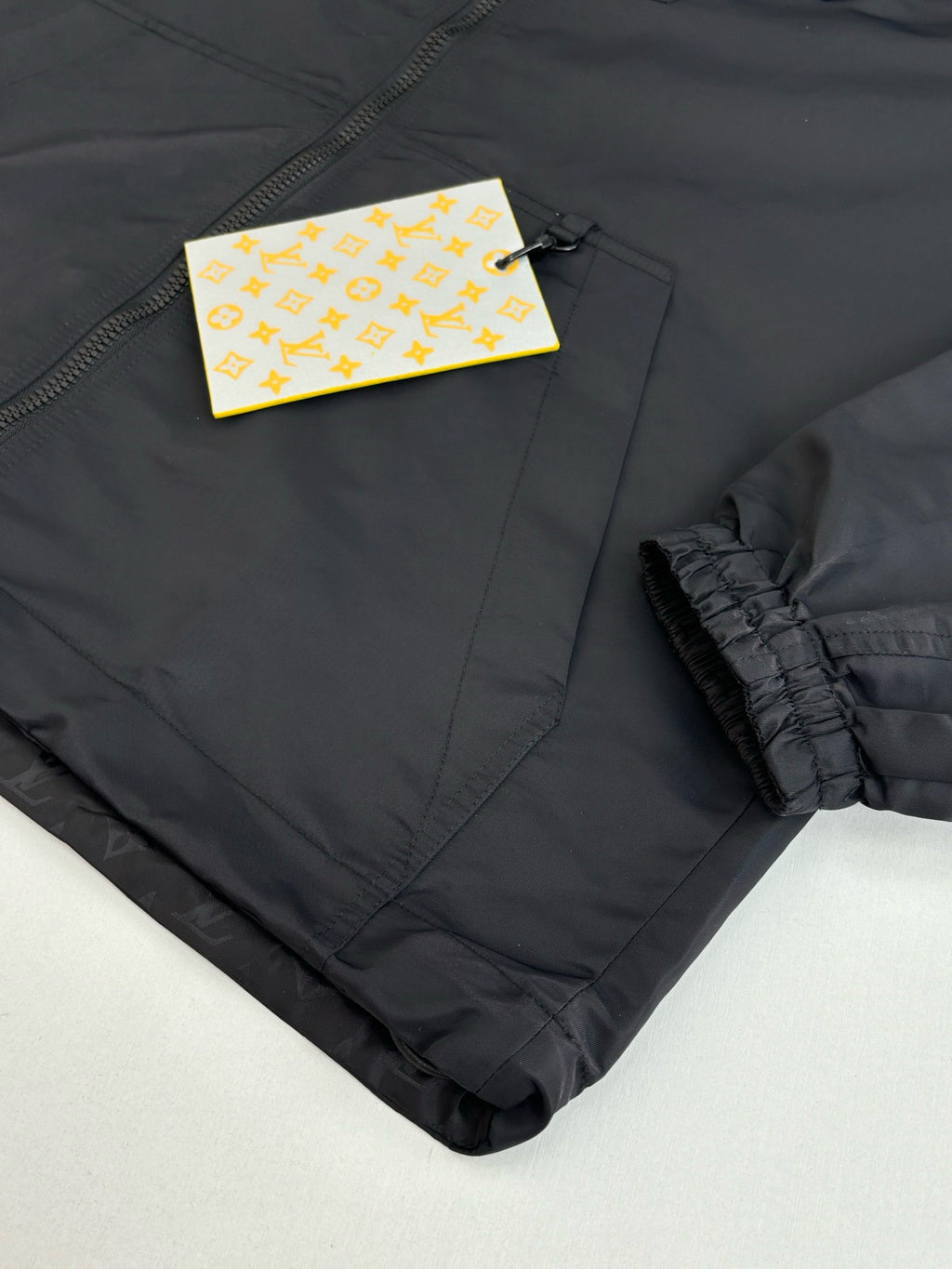 Dark navy zip jacket sleeve cuff detail with hang tags and elastic ruffle trim
