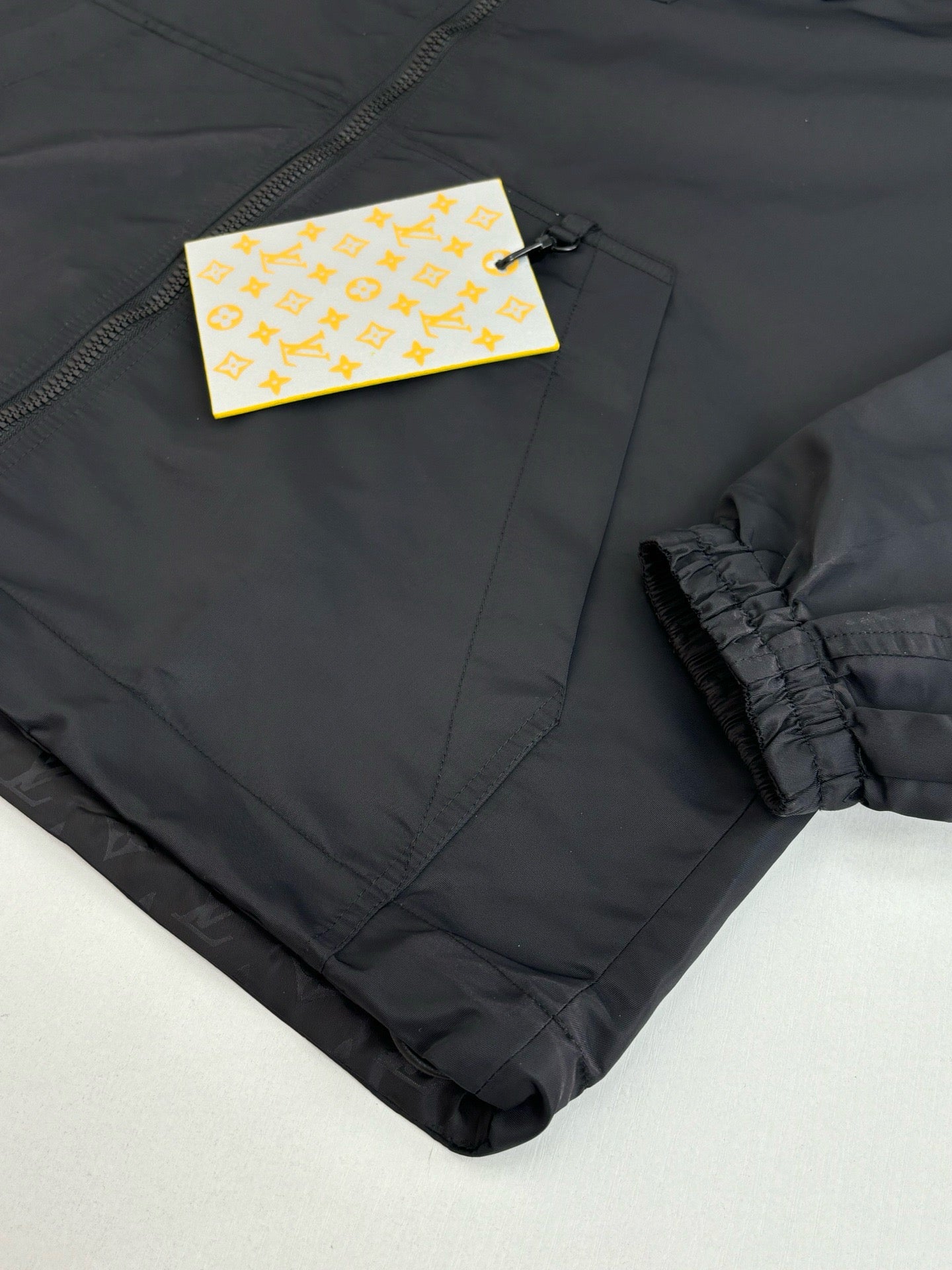 Dark navy zip jacket sleeve cuff detail with hang tags and elastic ruffle trim
