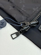 Dark navy jacket zipper pull and strap detail with black hardware, close-up