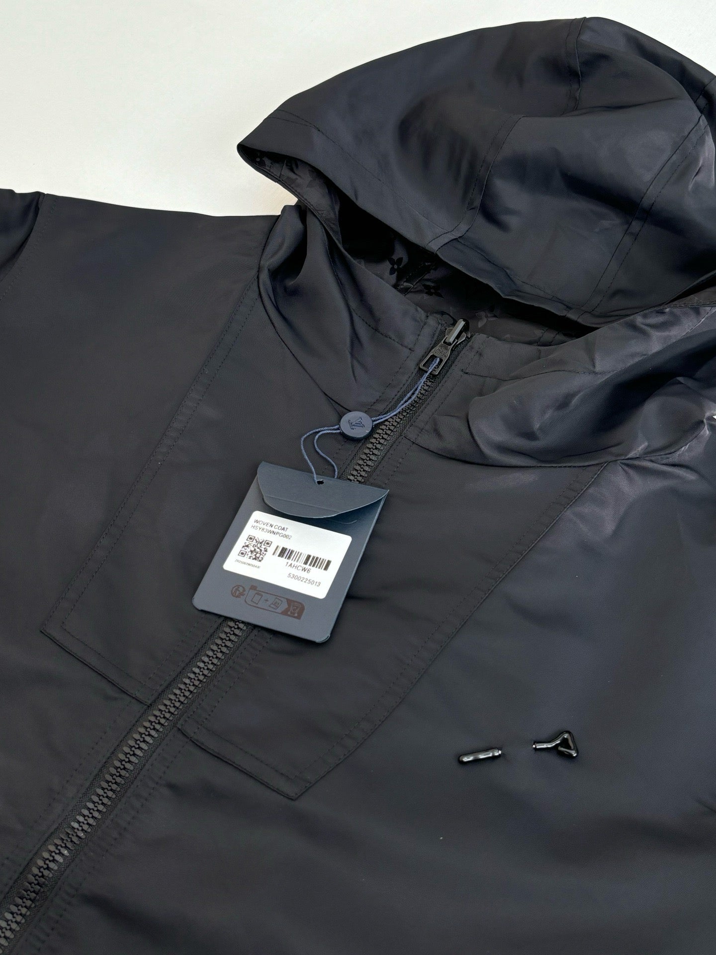 Dark navy hooded jacket with zipper and hang tag, neckline and zipper close-up