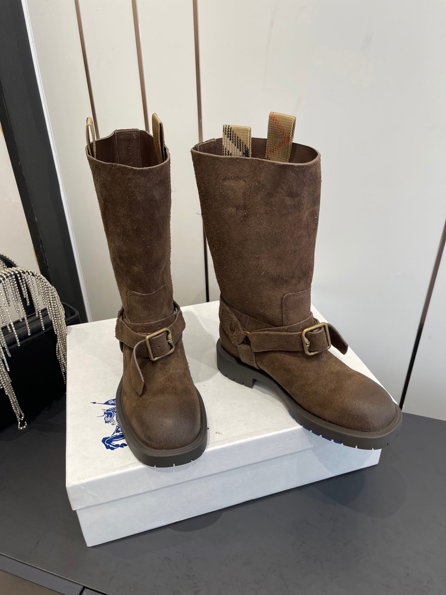 Dark brown suede tall boots with side buckles and low-profile sole, front view