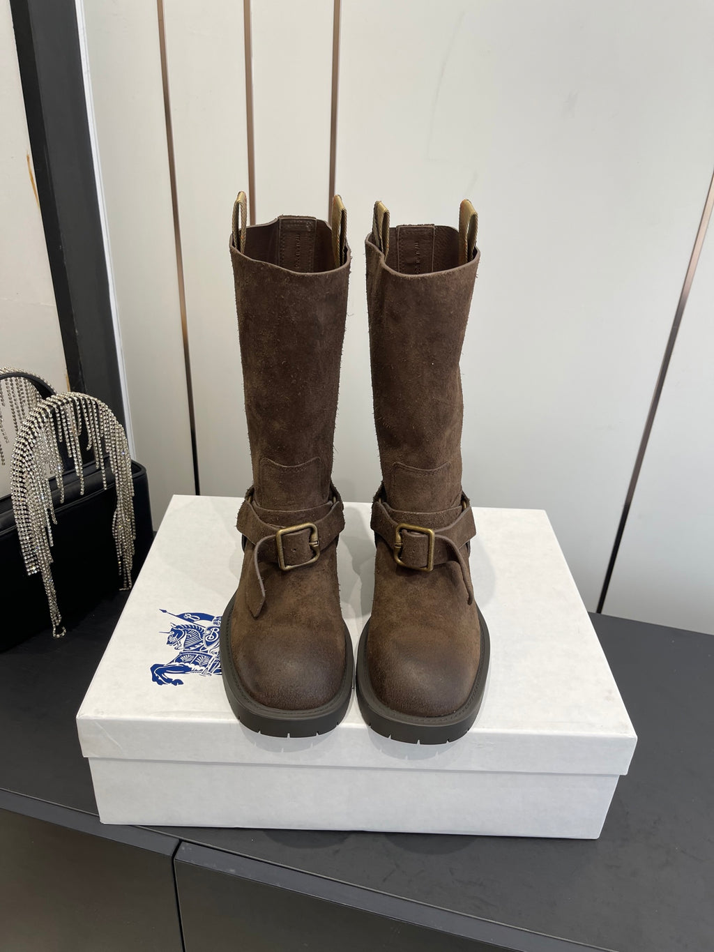 Dark brown suede tall boots with side buckle straps and low-profile rubber sole