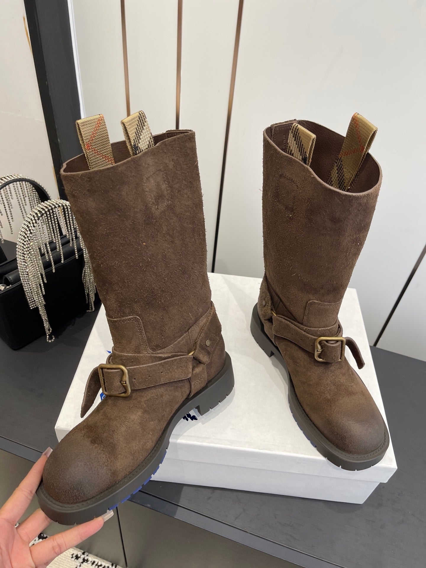 Pair of dark brown suede tall boots with side buckles and padded ankle cuffs