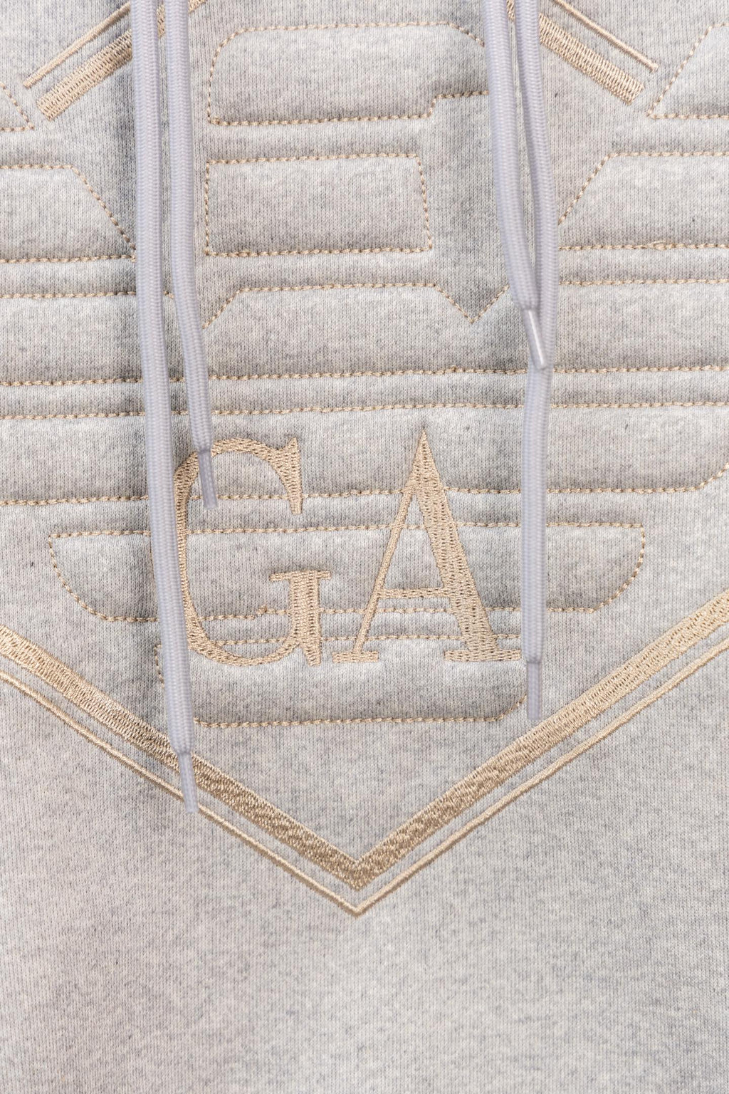Amiri hoodie close-up of embroidered V logo with gold-toned stitched lettering