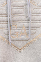 Amiri hoodie close-up of embroidered V logo with gold-toned stitched lettering
