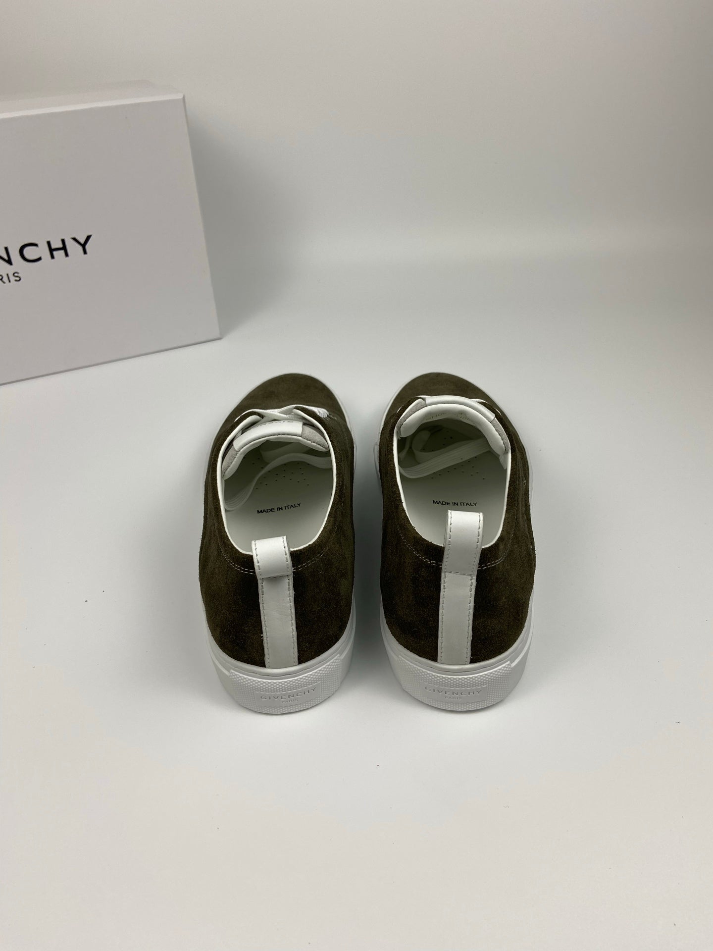 Olive suede sneakers from back view with white heel tabs and white rubber soles.