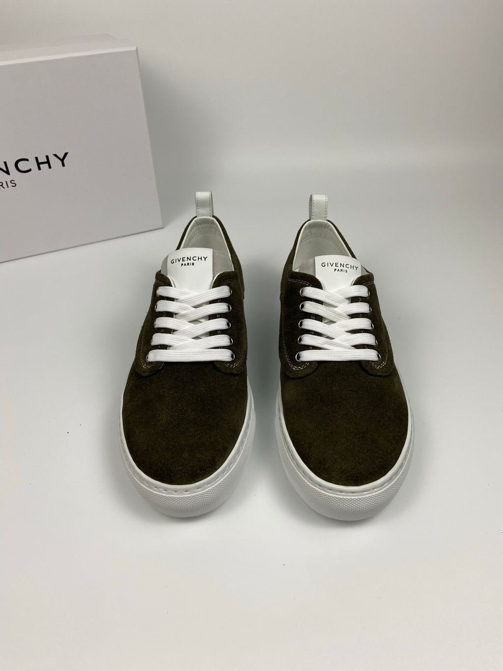 Pair of olive suede sneakers with white laces, white soles, and Givenchy logo at tongue.