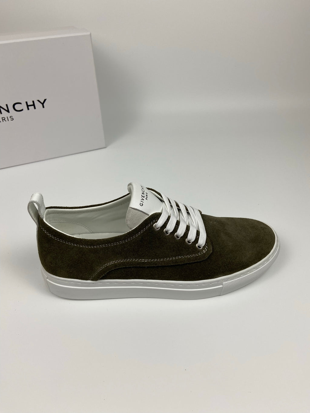 Olive suede sneaker with white laces and white rubber sole, side profile view.