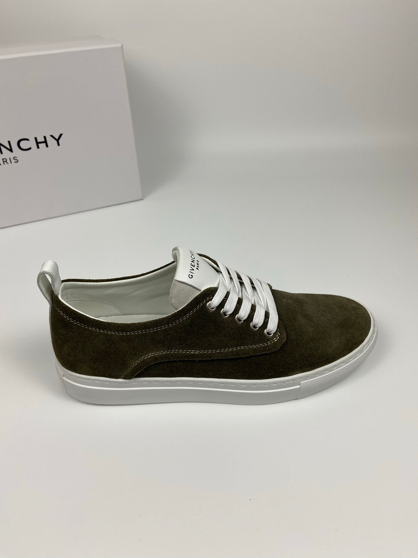 Olive suede sneaker with white laces and white rubber sole, side profile view.