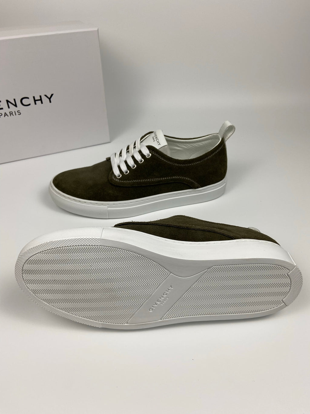 Olive suede sneakers with white laces; outsole sole view shows textured tread.