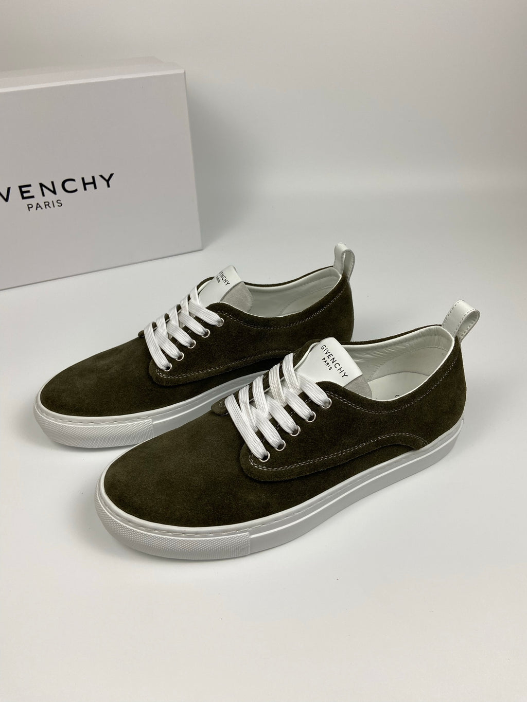 Olive suede sneakers with white laces and white soles, both shoes angled on display.
