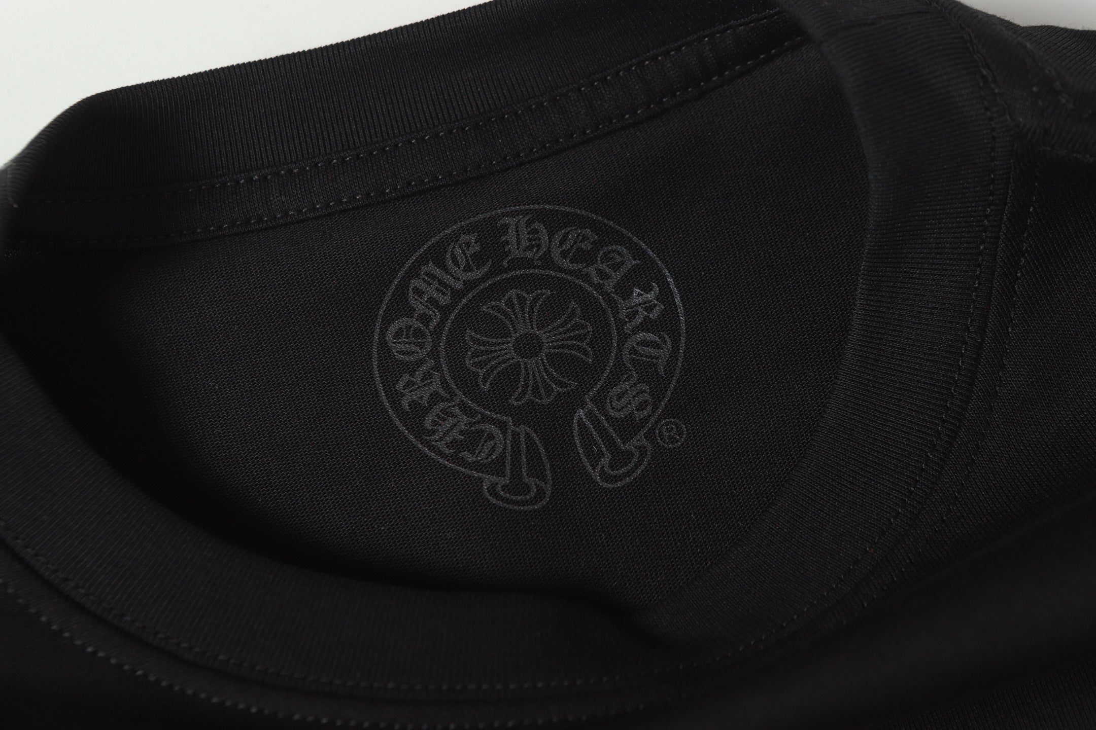 Black long-sleeve shirt close-up of subtle chest emblem logo and stitching detail