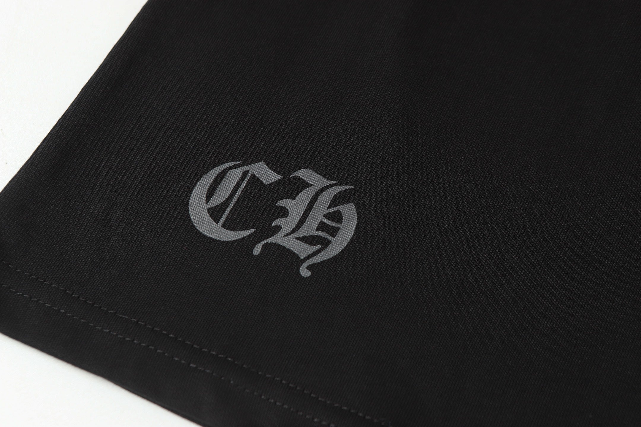 Black long-sleeve shirt sleeve cuff with small gray monogram emblem