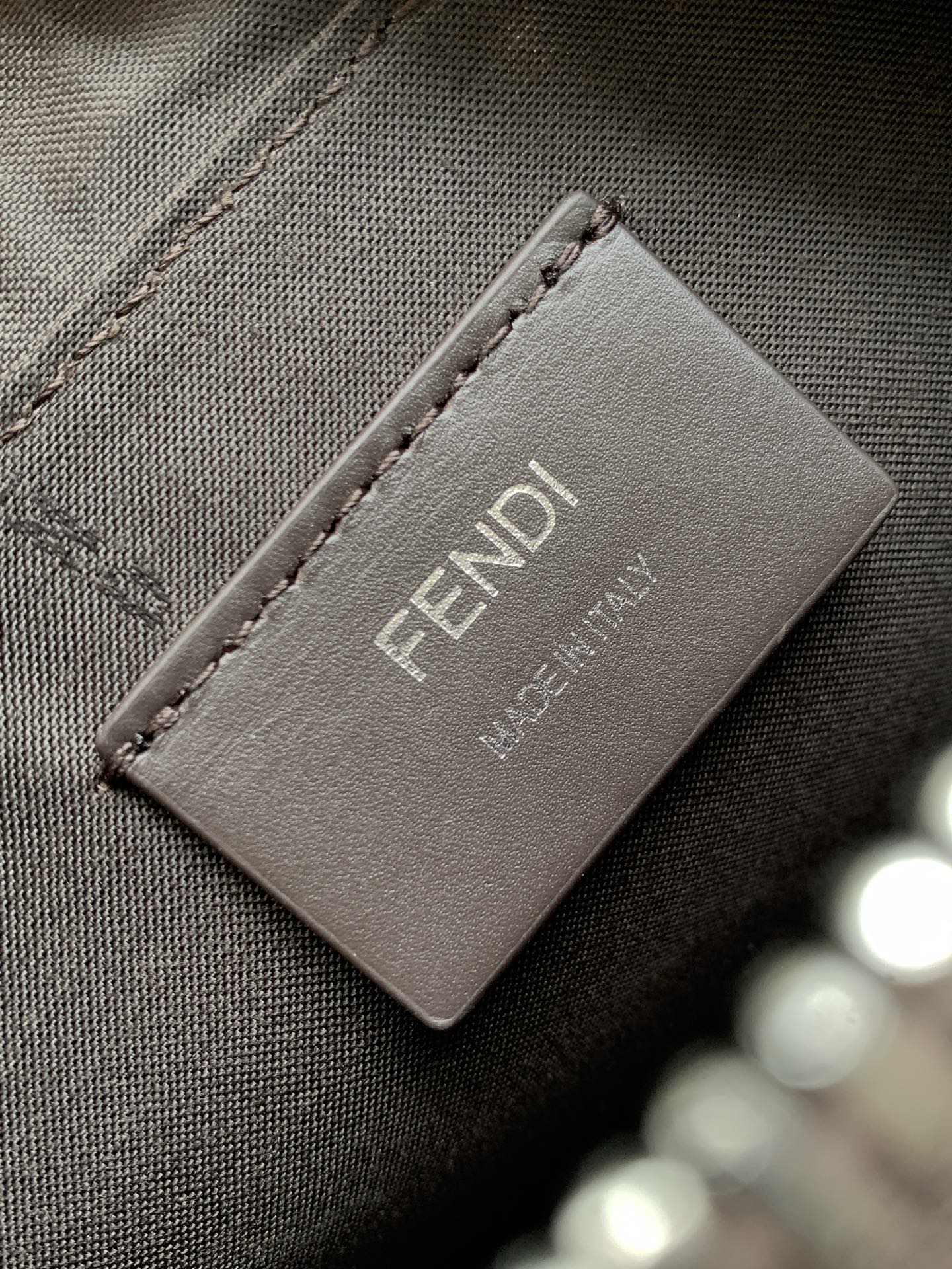 Fabric lining label with Fendi logo and small brand text on dark bag