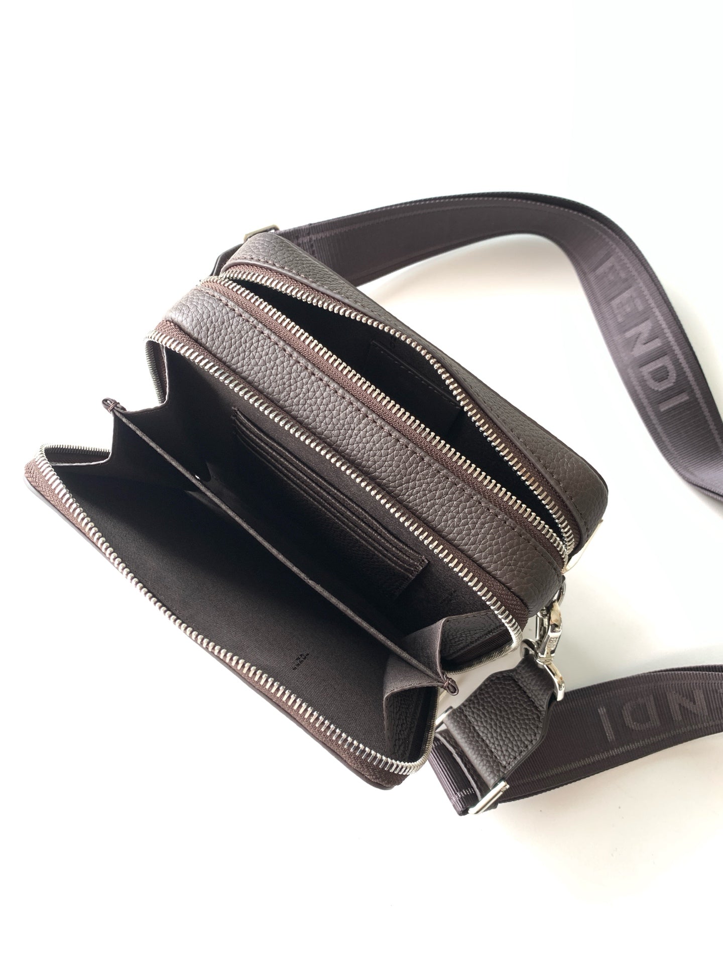 Mini crossbody bag showing open interior with zip pocket and webbing strap