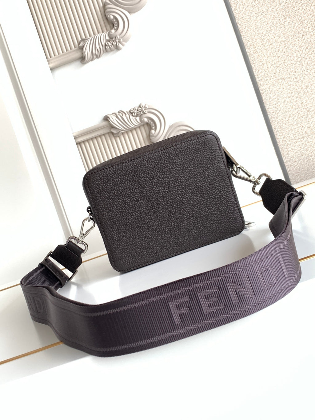 Leather crossbody bag with top zip and wide webbed strap; dark front panel