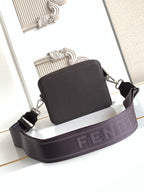Leather crossbody bag with top zip and wide webbed strap; dark front panel