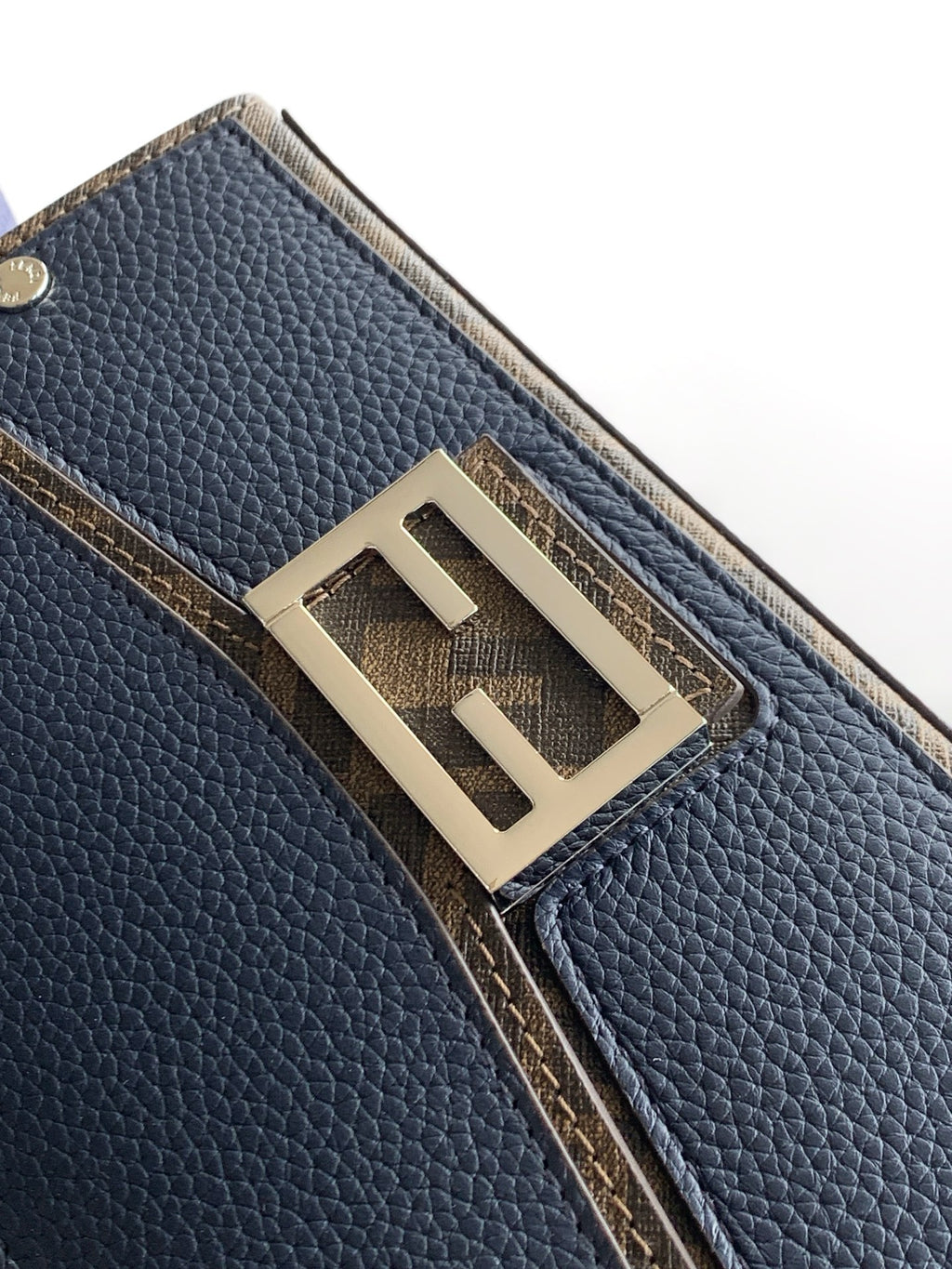 Fendi bag hardware close-up, gold-tone FF plaque on textured blue pebbled leather