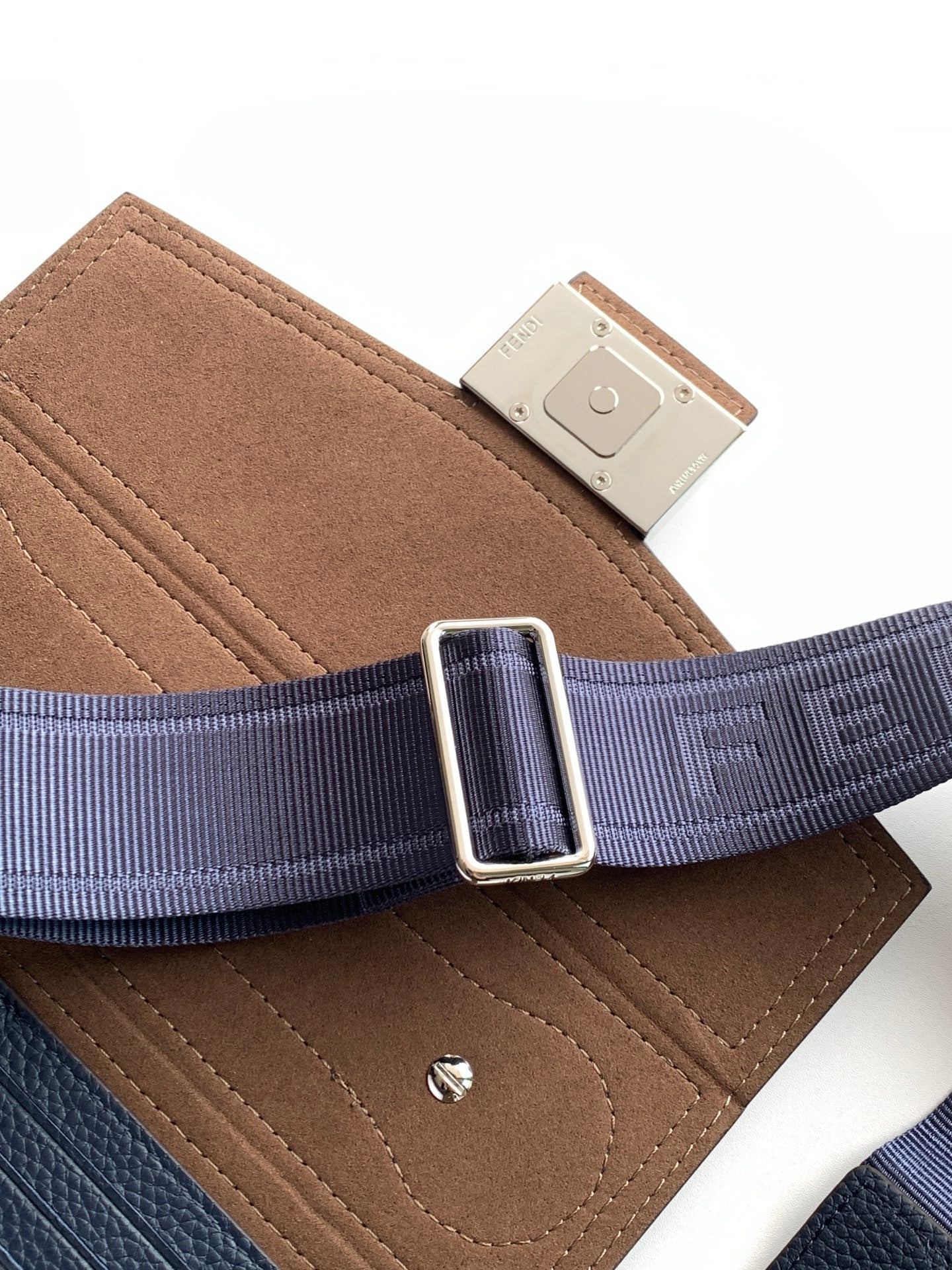 Fendi crossbody strap close-up with silver buckle, navy webbing and tan suede panel