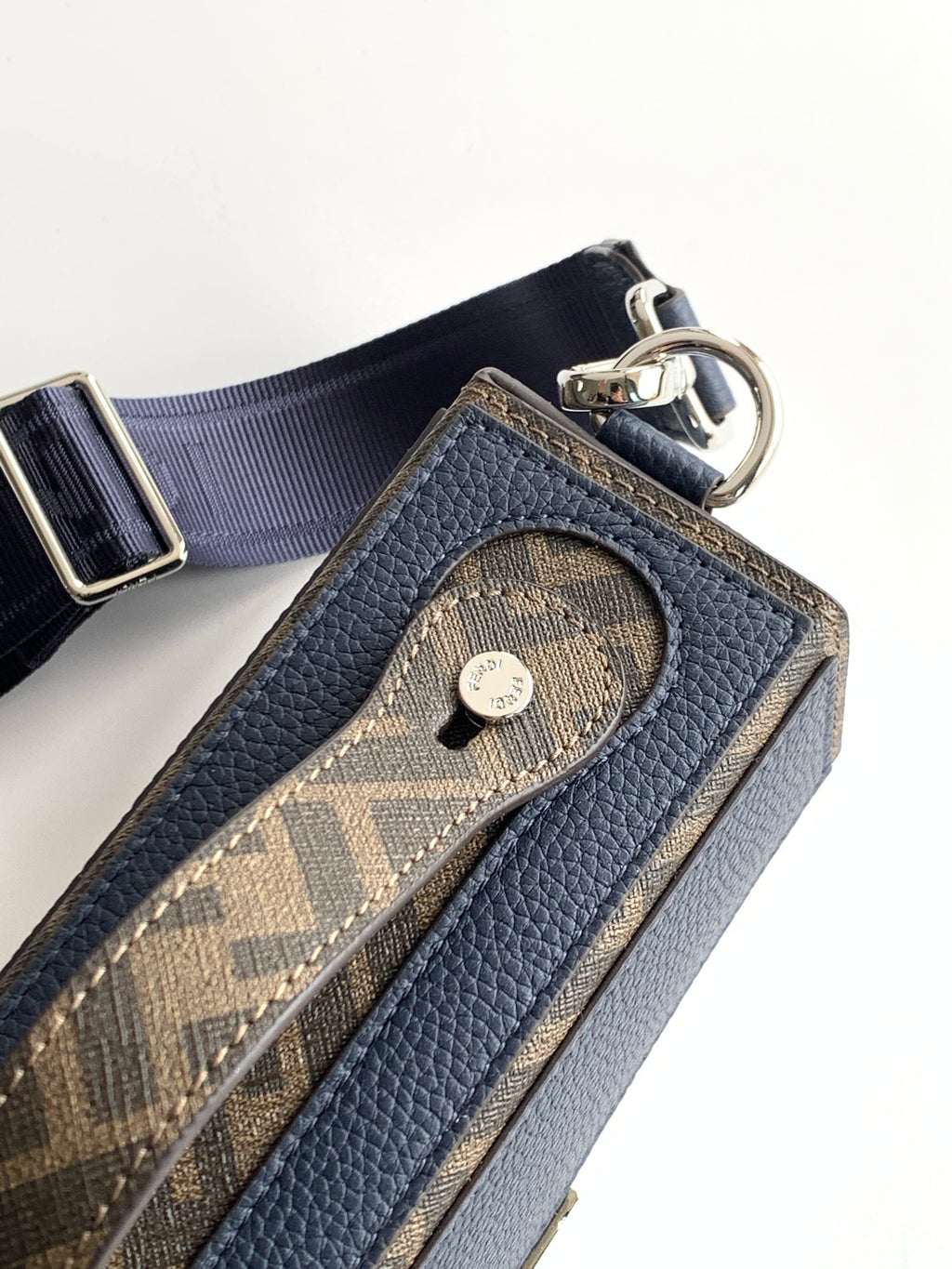 Fendi bag close-up with logo charm and pebbled blue leather pocket, metal rings and strap