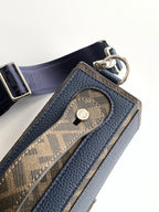 Fendi bag close-up with logo charm and pebbled blue leather pocket, metal rings and strap