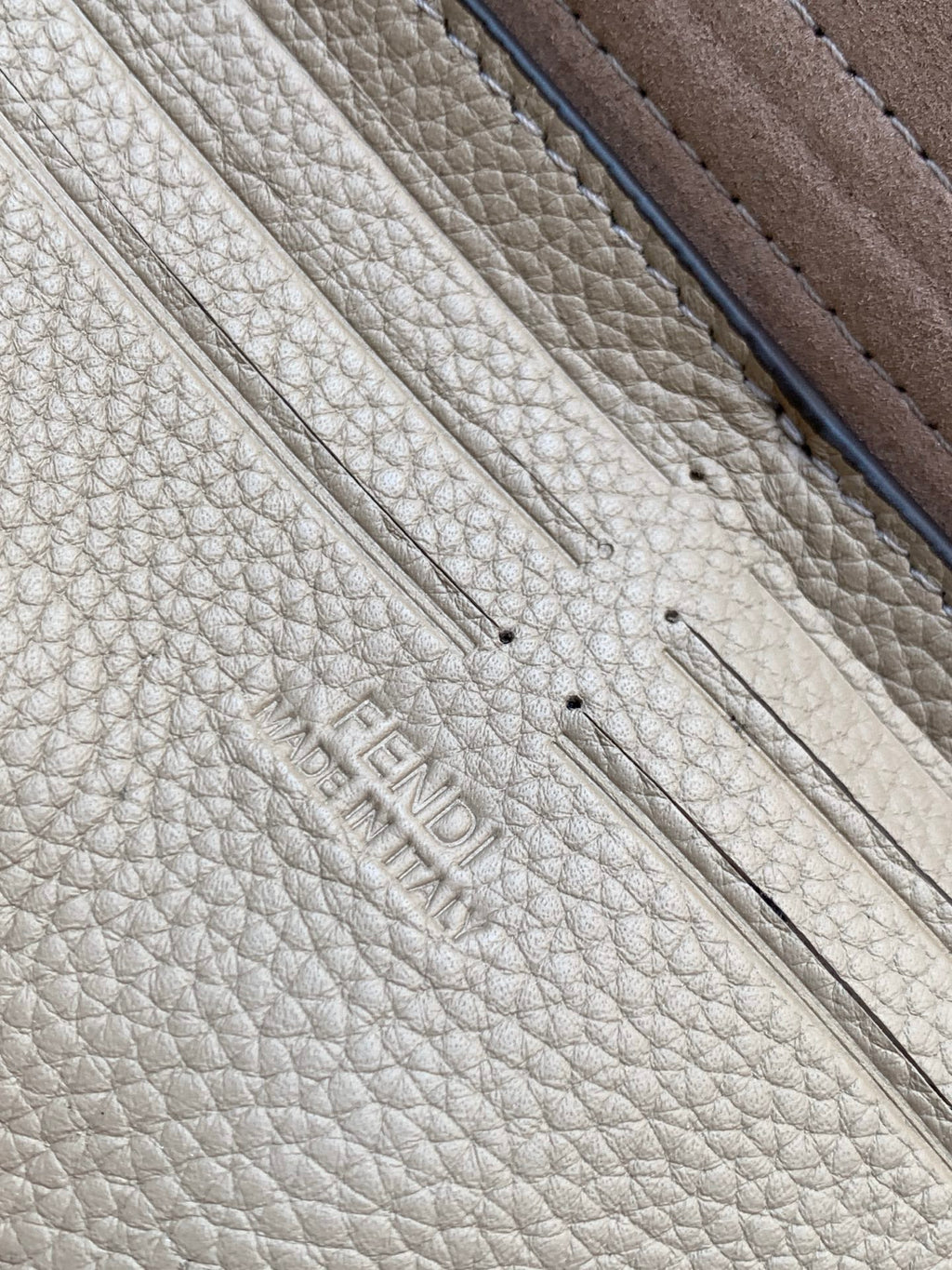 Fendi logo embossed on textured light-beige leather with dark edge trim