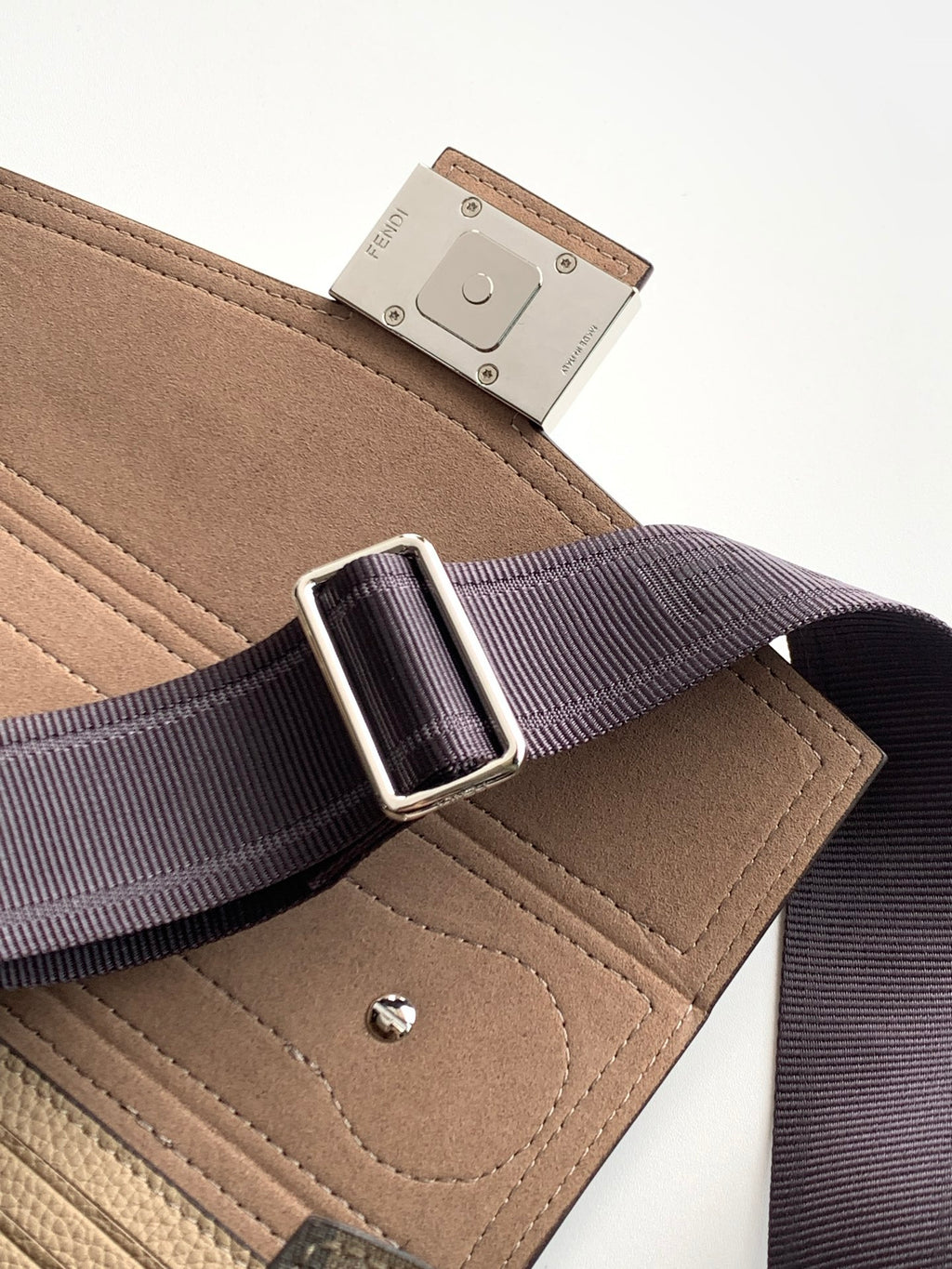 Fendi strap buckle on riveted leather tab attached to textured beige mini bag