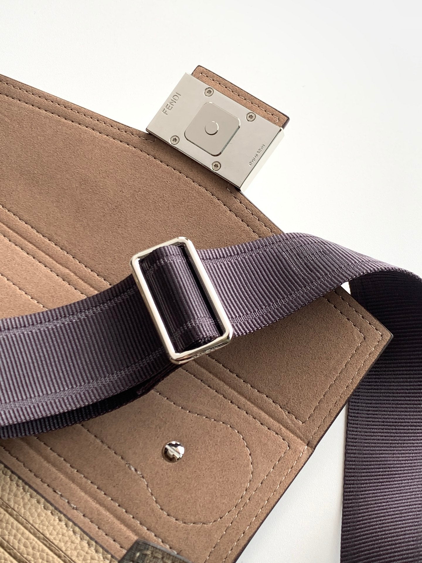 Fendi strap buckle on riveted leather tab attached to textured beige mini bag