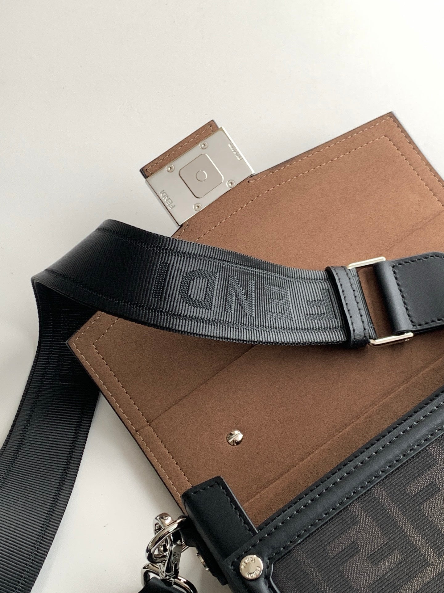 Fendi bag with dark webbed strap showing logo and tan interior flap