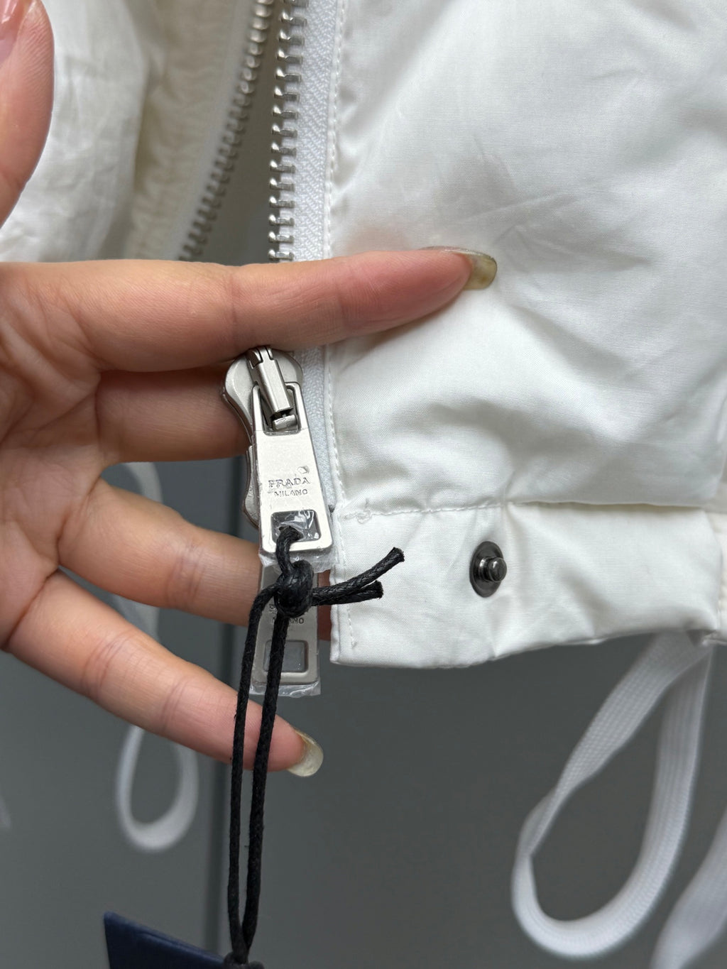 White puffer jacket zipper tape and hanging tie with metal pull tab