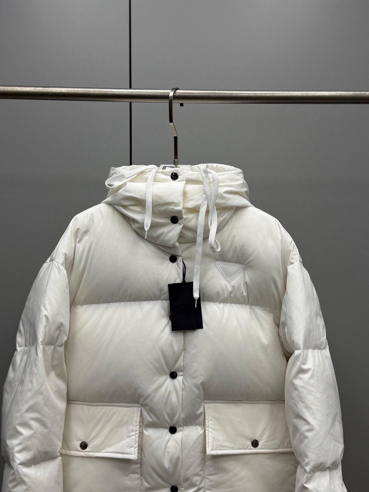 White hooded puffer jacket with buttoned front and flap patch pockets