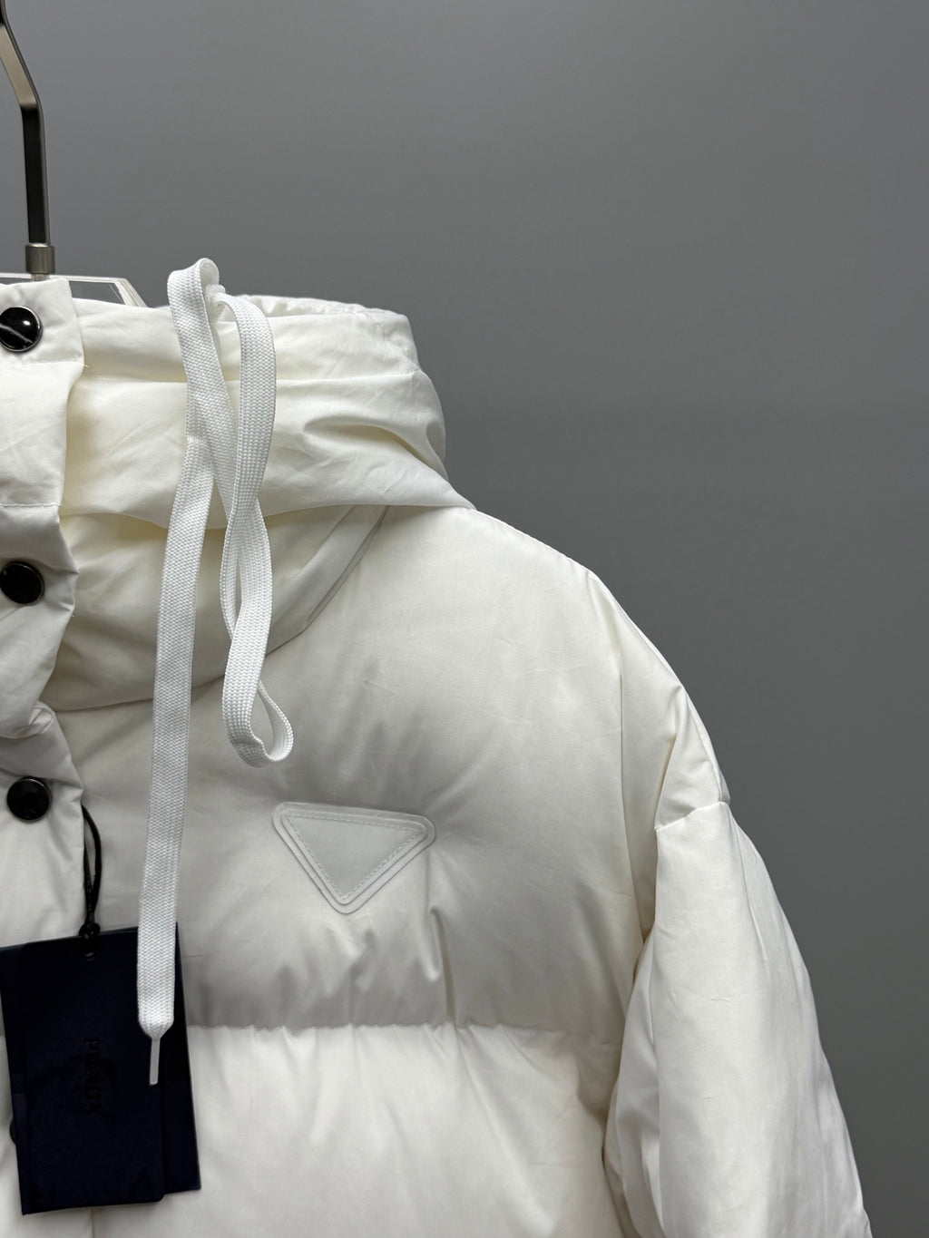 White puffer jacket with drawstring hood and triangular logo patch