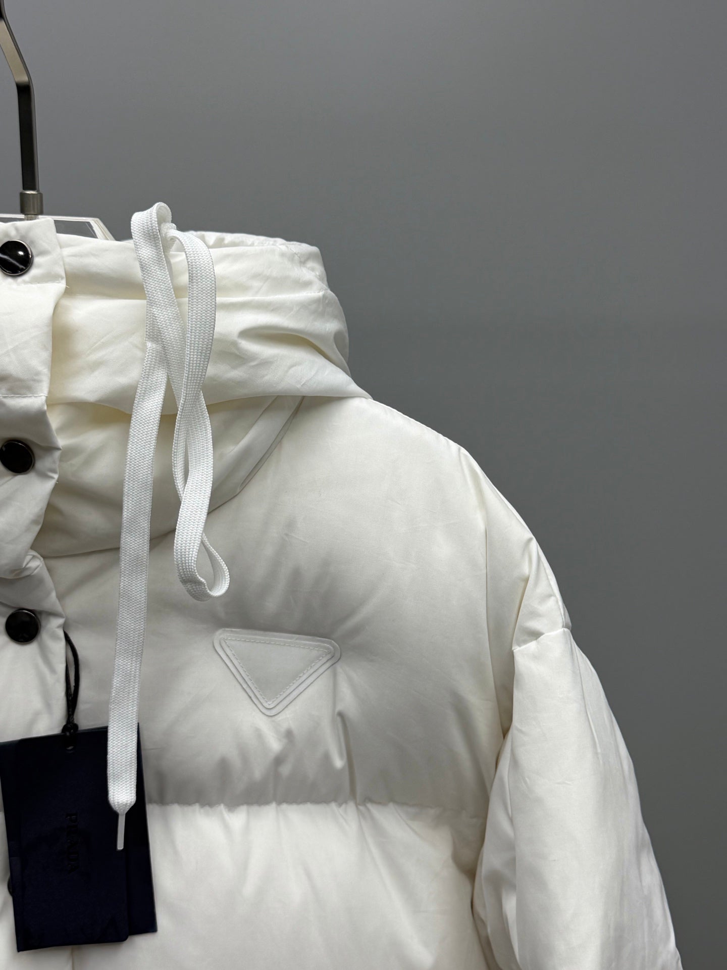 White puffer jacket with drawstring hood and triangular logo patch